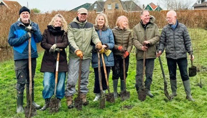 een groep anthousiaste vrijwilligers poseert voor project Oostzaan